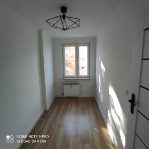 duzy jasny pokoj, drewniane panele, nowoczesny grzejnik, czarna stylowa lampa