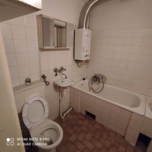 lazienka przed remontem, stara wanna i wc, plytki w kolorach bezu i bieli